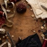 A flat lay of sewing notions scattered across a worn wooden table — thread spools, buttons, scissors, measuring tape, pin cushion, and pattern tissue paper — with one conspicuous empty space where the seam ripper should be.